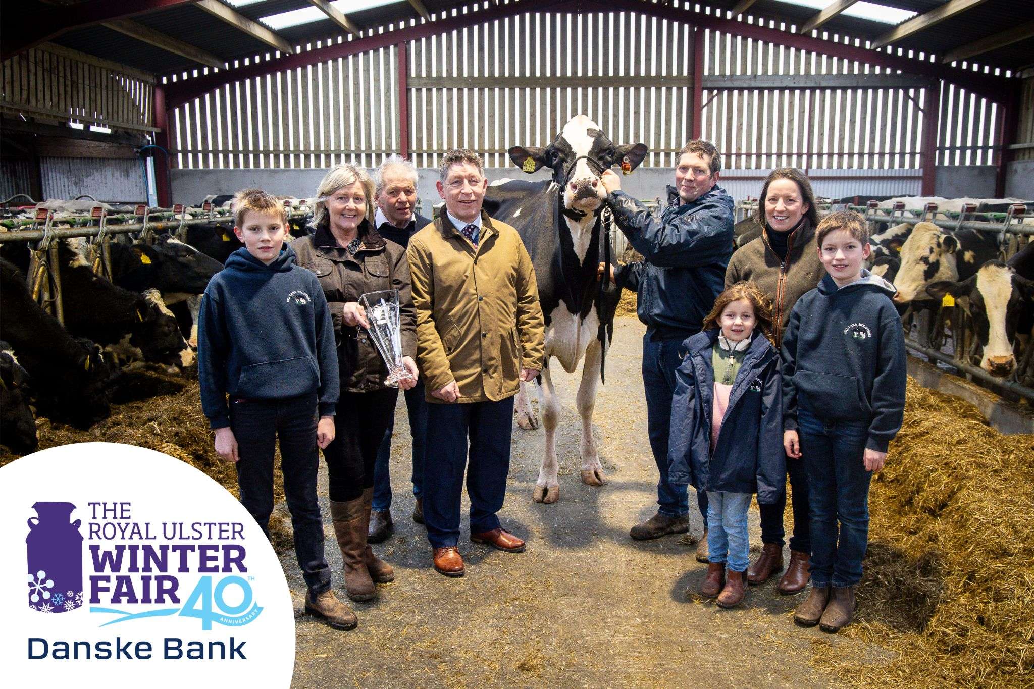 2025 winning exhibitors in a cattle shed with their winning cow and Show representatives